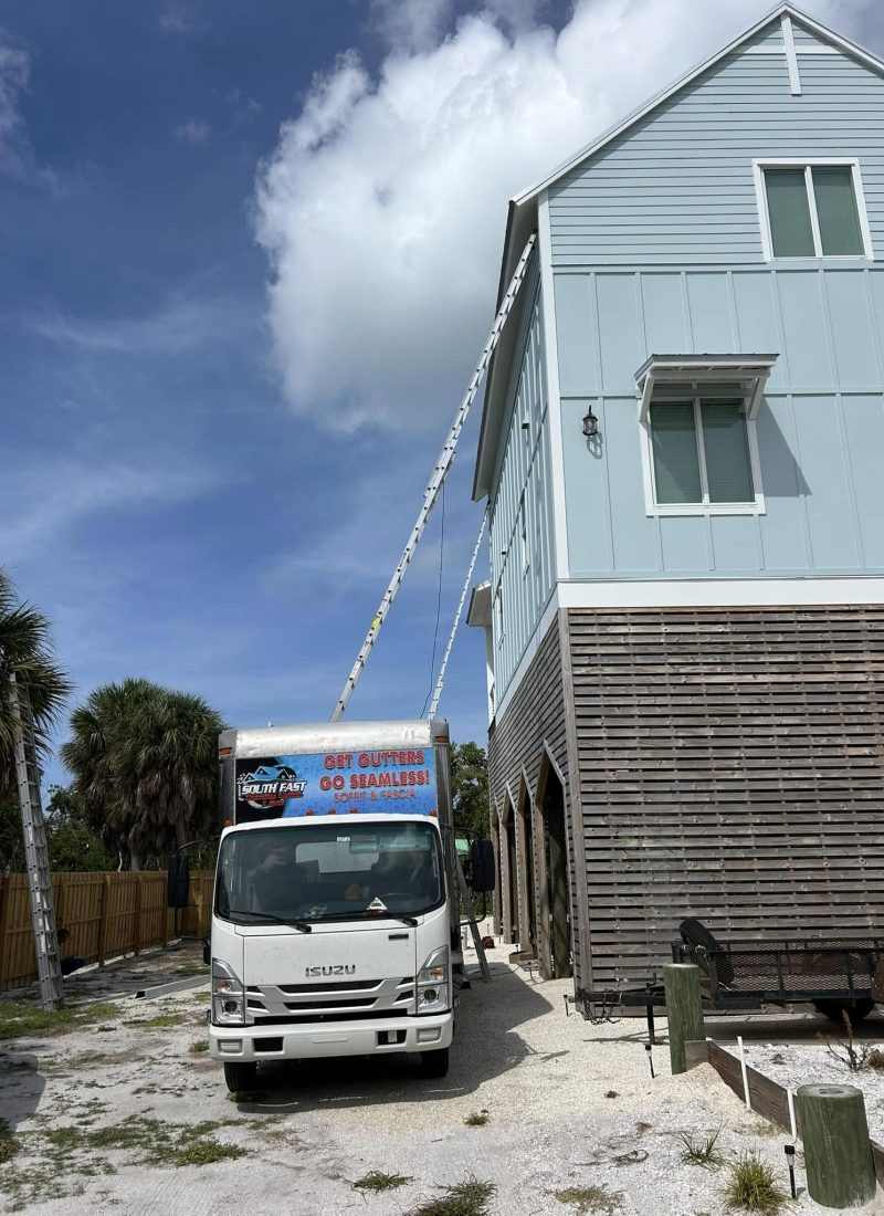 Seamless gutter installation truck parked outside a house performing an emergency gutter